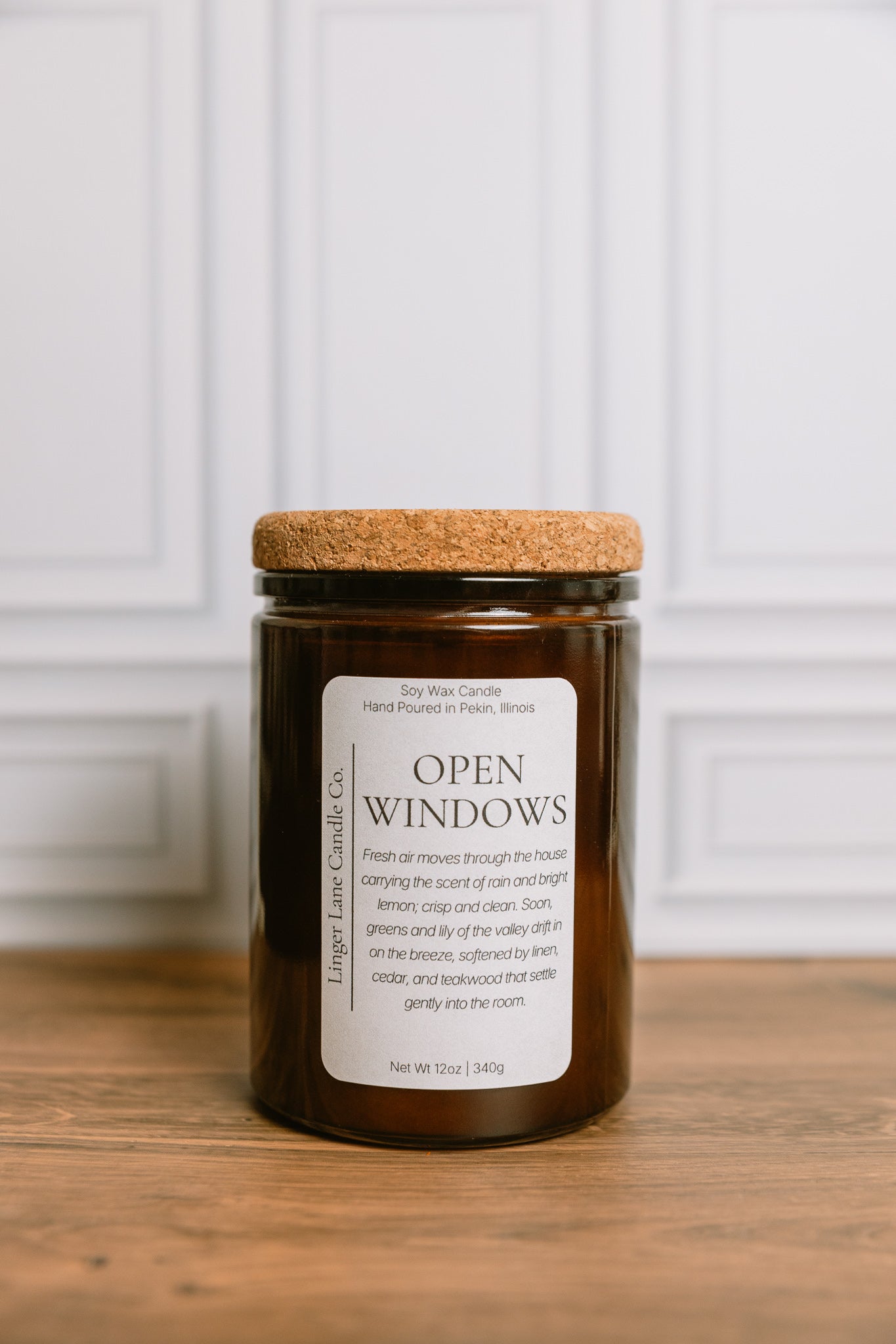 Dark amber colored recycled glass Candle jar labeled 'Open Windows' with a cork lid on a wooden surface.