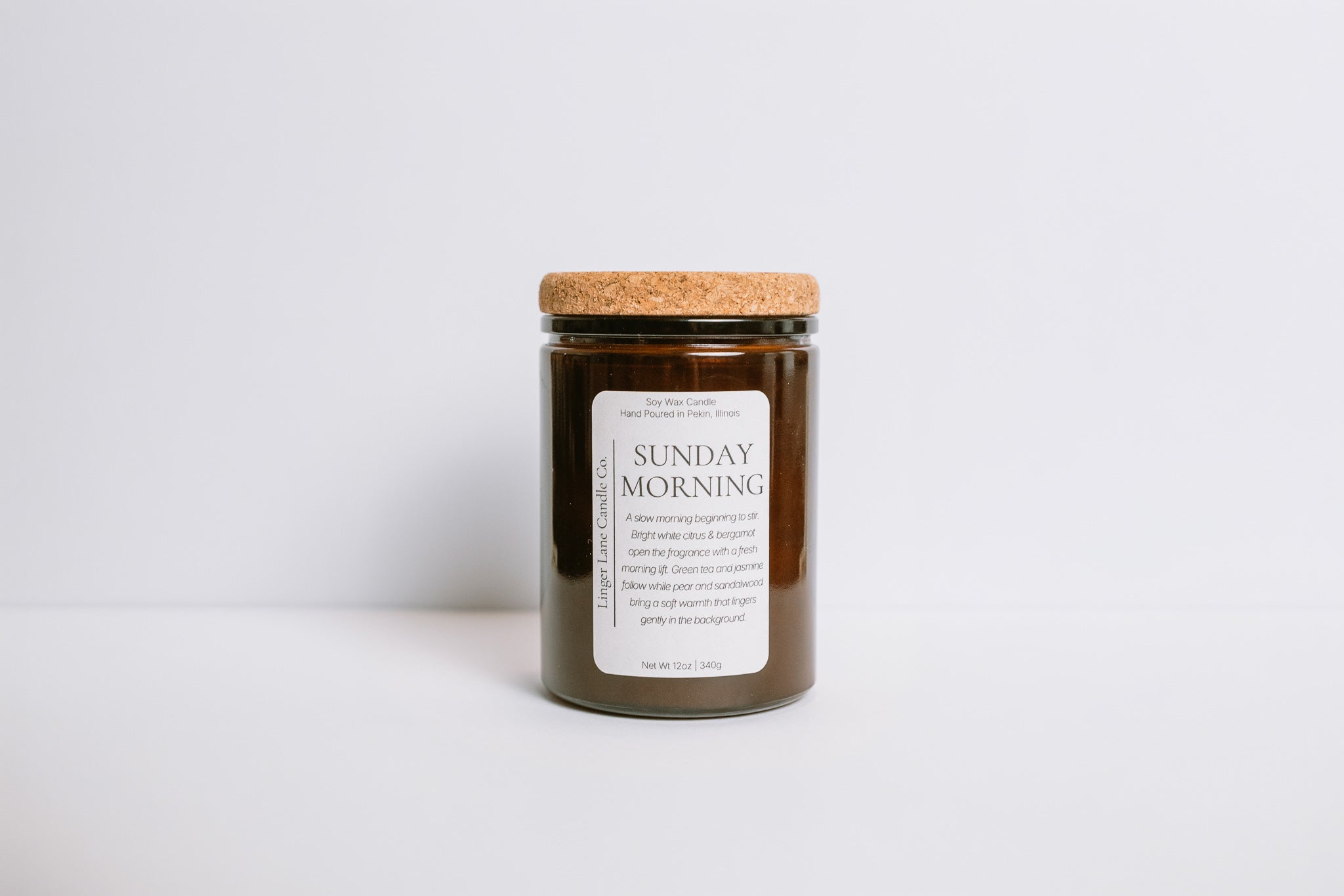 Dark brown glass Candle jar with cork lid and 'Sunday Morning' label on a white background