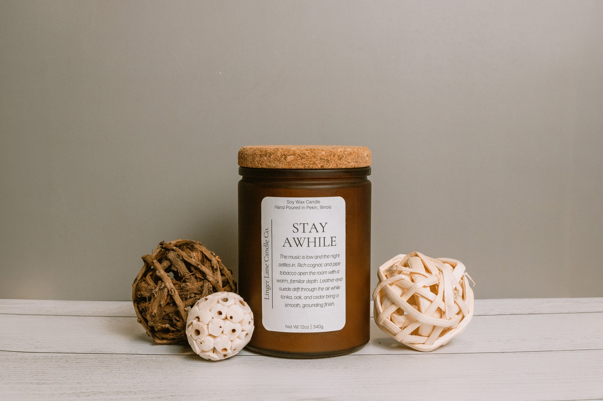 Soy wax candle in a frosted amber Candle jar labeled 'Stay Awhile' with decorative elements on a neutral background