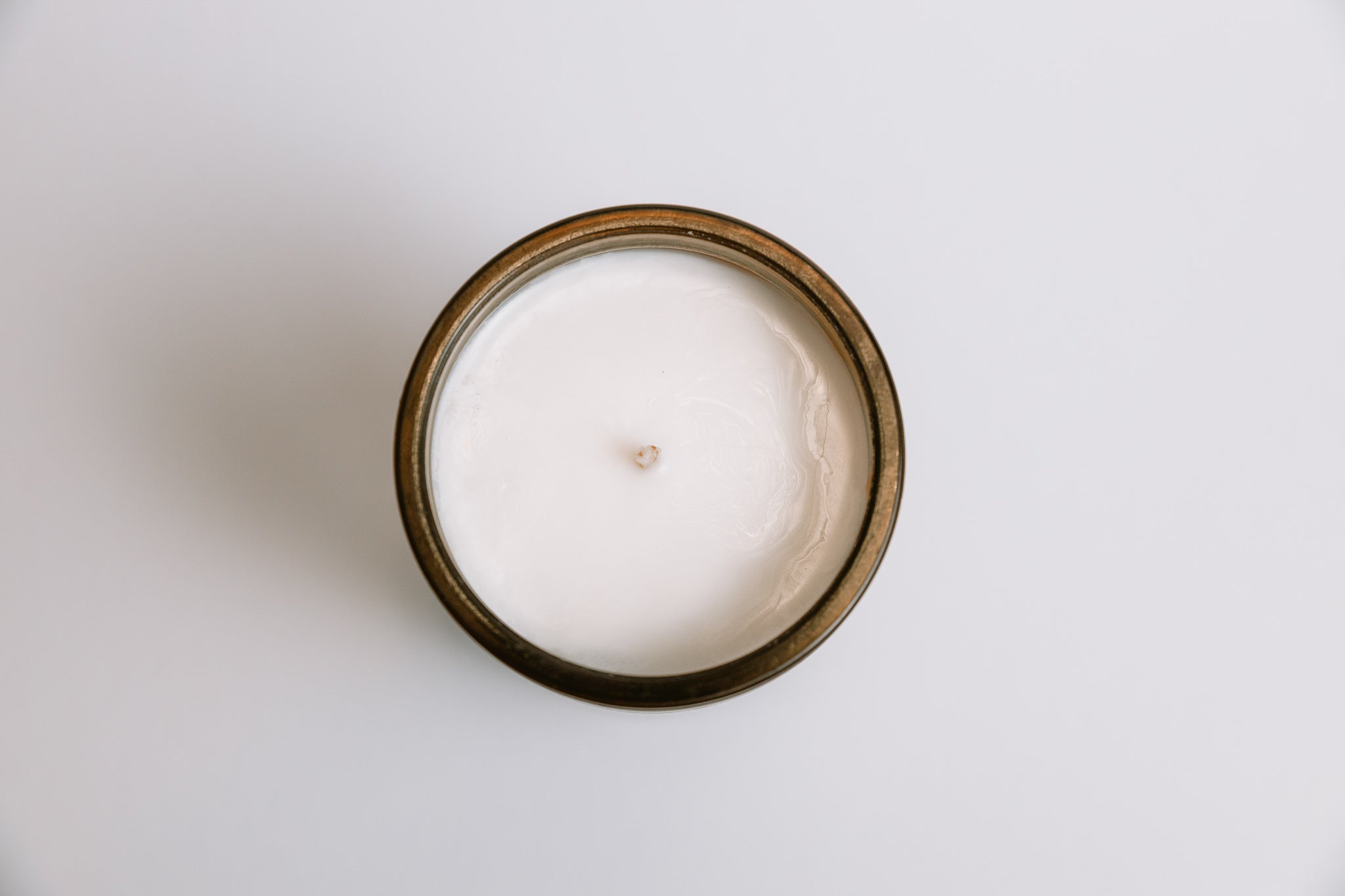 White soy candle in a glass jar on a light gray background