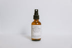 Scented odor eliminating room spray in an amber bottle labeled 'Open Windows' on a white background