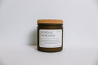 Soy Candle in a jar with cork lid labeled 'Sunday Morning' on a light background