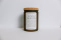 Soy candle in a frosted amber jar with a cork lid on a white background