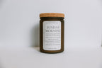 Soy candle in a frosted amber jar with a cork lid on a white background