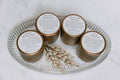 Four candles with labels on a glass tray on a marble surface