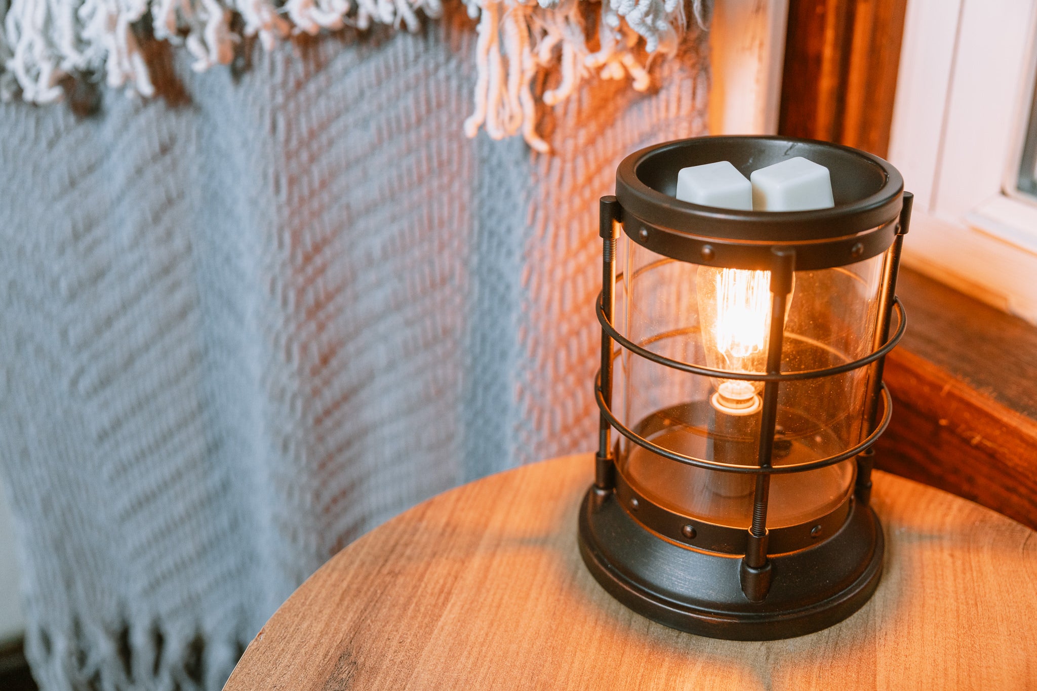 Decorative lantern wax warmer with an Edison light bulb inside on a wooden surface