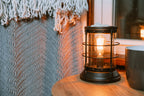 Vintage-style wax warmer with wax melts on a wooden surface with a textured wall and cup in the background